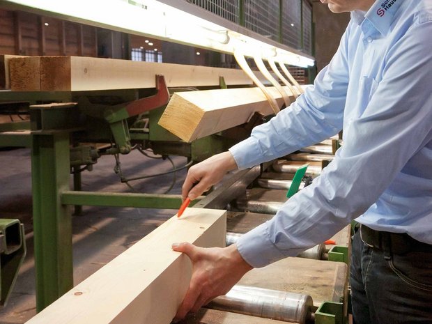 Messung und Anpassung von Holz durch Person in der Produktionshalle der SchwörerHaus KG